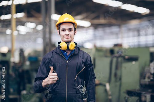 technician standing and thump up at machine in factory