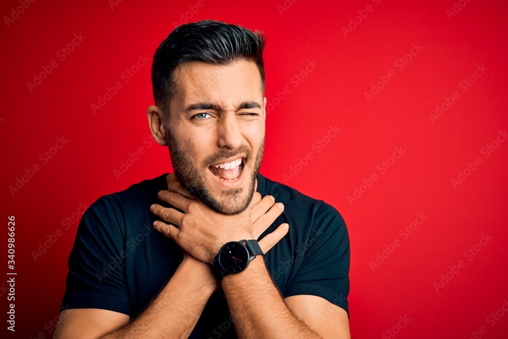 Young handsome man wearing casual black t-shirt standing over isolated red background shouting and suffocate because painful strangle. Health problem. Asphyxiate and suicide concept.