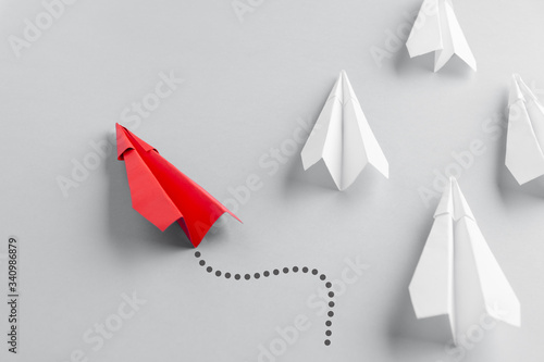 Red paper plane as a leader. White planes follow him. White background. Change of course