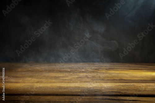 An old wooden table on a black background with smoke