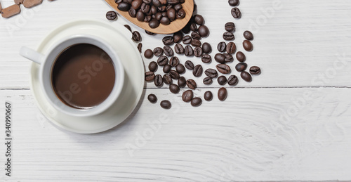 Cup of black coffee and coffee beans good essentials on white wooden background. Top view.