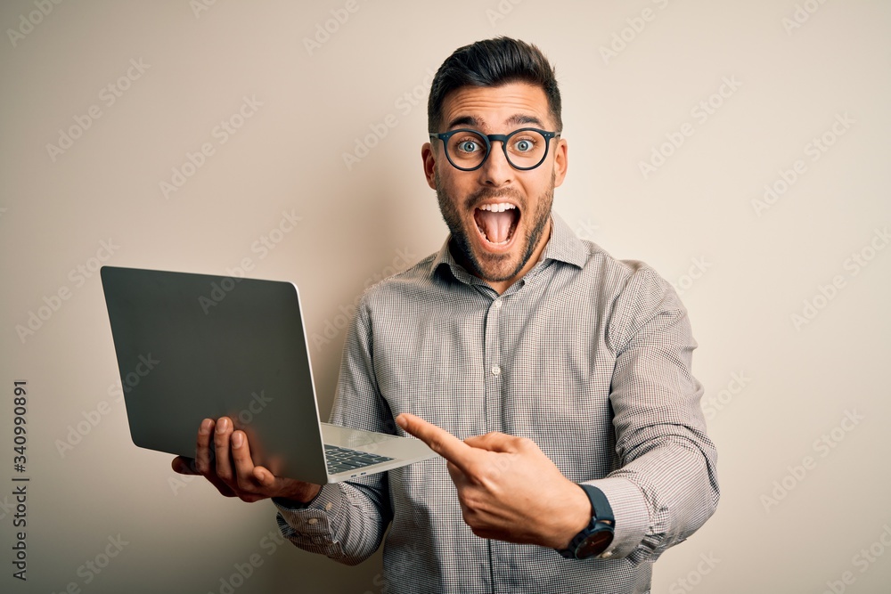 Young business man wearing glasses working using computer laptop very happy pointing with hand and finger Young business man wearing glasses working using computer laptop very happy pointing with hand and finger