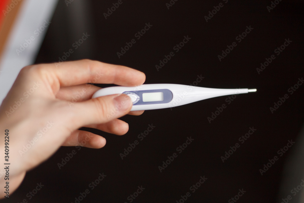 electronic thermometer in hand close up with body temperature