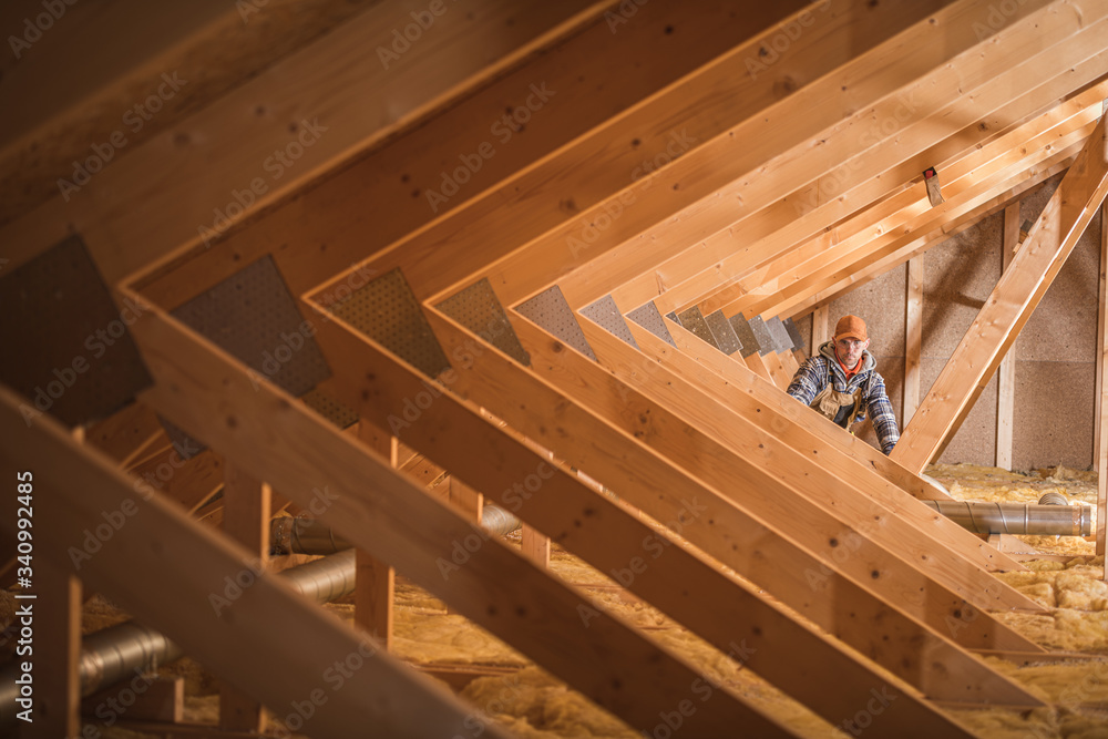 Construction Worker Insulating Attic Space Of Home. Construction Worker Insulating Attic Space Of Home.