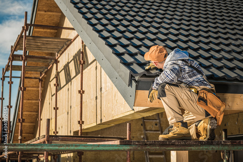 Male Roof Contractor Reviews Project Progress.