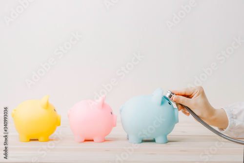 Doctor using stethoscope to check 3 piggy bank in queue. Concept check saving money and financial sustainability