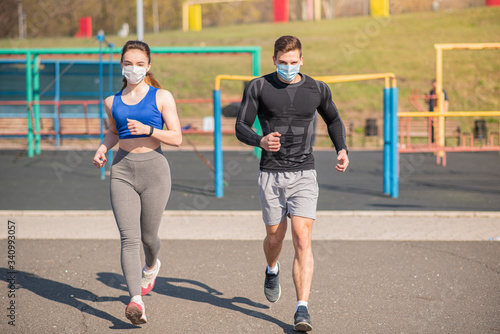 A young guy and a girl in medical masks run around on the playground during a pandemic. COVID-19. Health care. photo