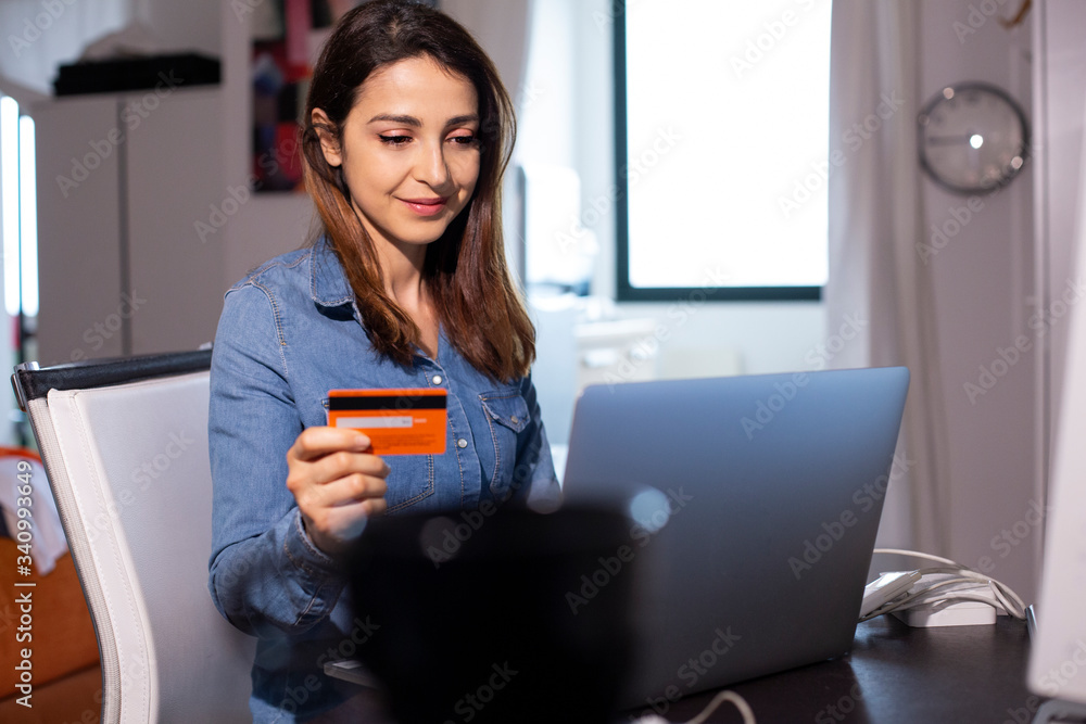 Giovane donna fa un ordine con la carta di credito seduta di fronte al suo iPad a casa sua Giovane donna fa un ordine con la carta di credito seduta di fronte al suo iPad a casa sua
