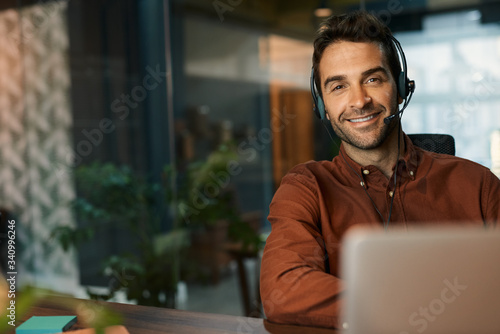 Smiling businessman talking on a headset in his office photo