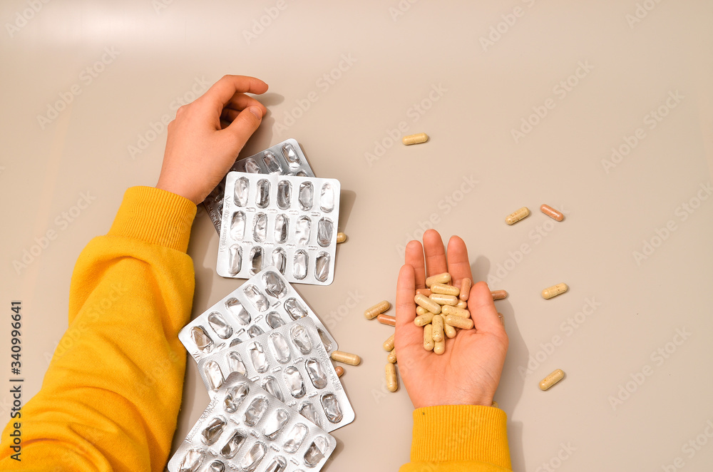 Obraz premium Hands with pharmaceuticals antibiotics pills medicine. colorful antibacterials pills on beige background. capsule pill medicine. Simbol of 2020 year, cronavirus broblem