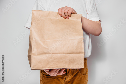 Brown craft paper bag for the removal or delivery of goods and food in hands on a white background. Place for advertising. delivery service concept