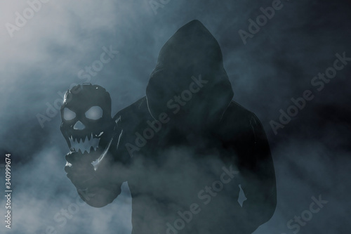 Man dressed in black holds the mask of a skull.