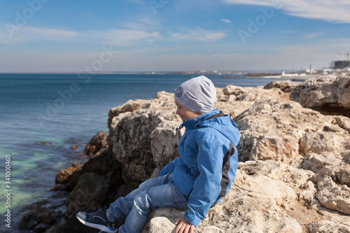 happy child walks on the sea coast, a child climbs stones