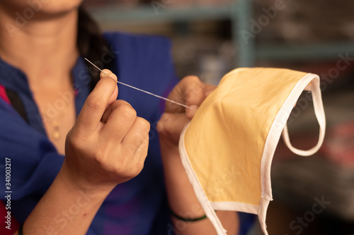 Closeup of Girl hand Knitting DIY face mask at home to protect from covid-19 or coronavirus pandemic at India - Due to shortage of Medical masks woman in India making masks .