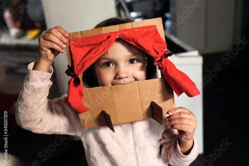Caucasian girl child plays in a cardboard theater