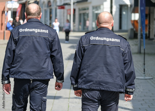 Konzept Ordnung und Sicherheit: Zwei Mitarbeiter des Ordnungsamtes in Uniform auf Streife in der Innenstadt - selektiver Fokus