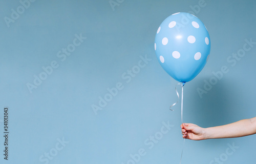 stylish birthday party or holidays with balloons close up. Hand  holding blue  balloon isolated on blue background with copy space for text. background for birthday greeting card 