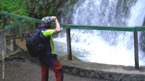 Man walking in the nationl park and admiring the waterfall
 photo