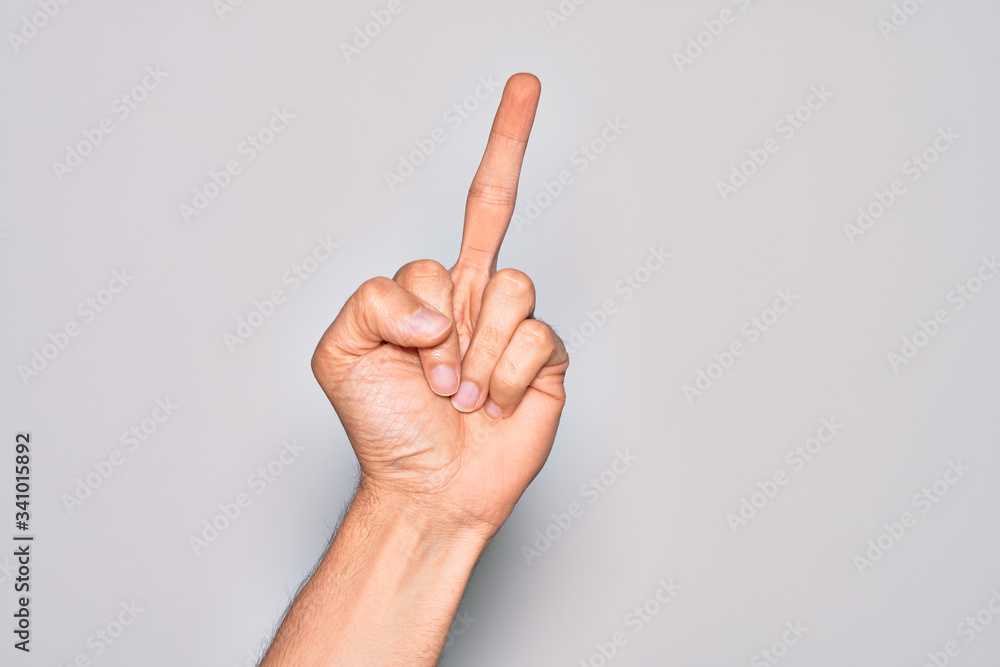 Hand of caucasian young man showing fingers over isolated white background showing provocative and rude gesture doing fuck you symbol with middle finger Hand of caucasian young man showing fingers over isolated white background showing provocative and rude gesture doing fuck you symbol with middle finger