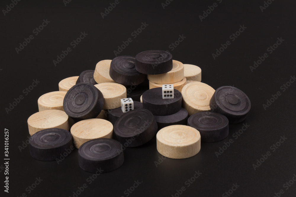 Backgammon. Board game. White dice and white and black chips for playing on a black background. Game for recreation Backgammon. Board game. White dice and white and black chips for playing on a black background. Game for recreation