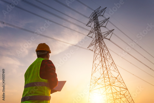 Asian Manager Engineering in standard safety uniform working inspect the electricity high voltage pole. photo