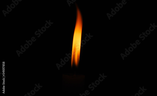 Lit flame of a candle on dark background 