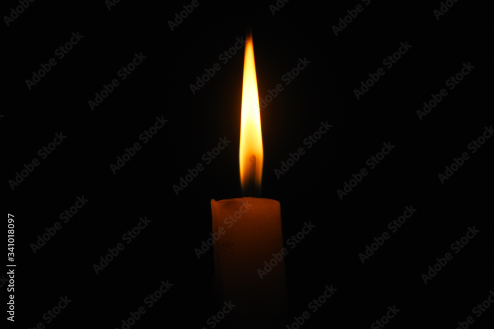 Lit flame of a candle on dark background Lit flame of a candle on dark background