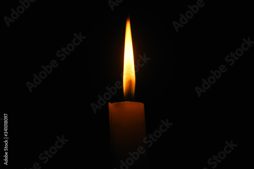 Lit flame of a candle on dark background 