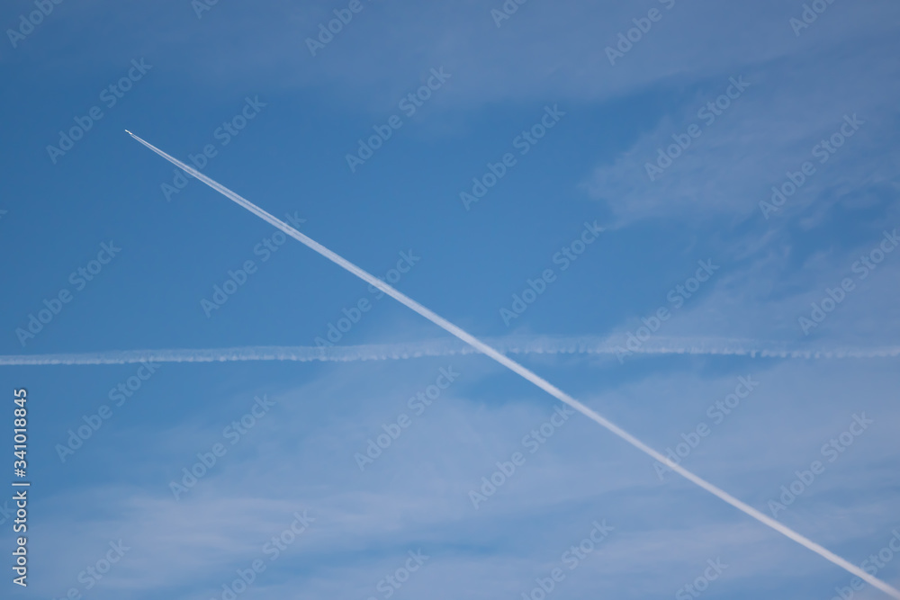 Two traces from planes crossing in the sky blue sky with some thin clouds