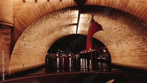 Shimmering French flag attached to the stern of a motor boat against the backdrop of the Elfel Tower at night. the ship swims under the bridge photo