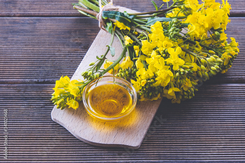 a cup with rapeseed oil next to it are rapeseed flowers on a plate