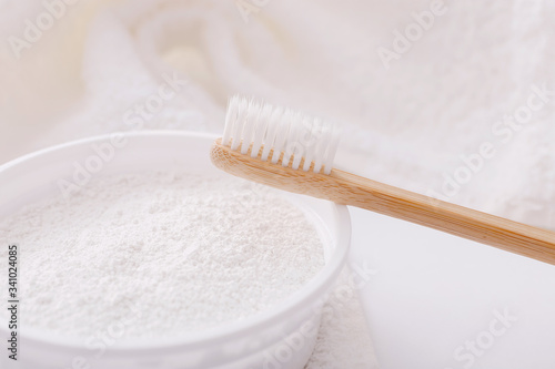 Wooden teeth brush and tooth-powder on white towel backgroud. Zero waste concept