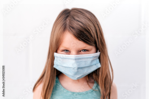 portrait of a girl with blue eyes wearing an anti-virus mask with intense assertive positive gaze looking straight to the camera photo