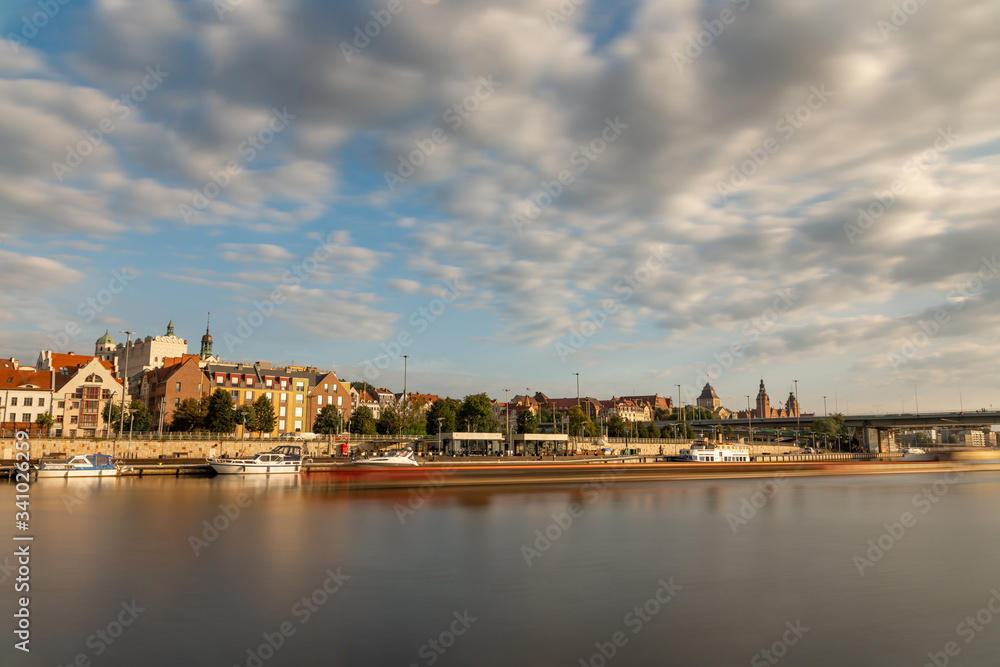 Historic buildings in Szczecin behind the Odra River. Blurry ship Long exposure