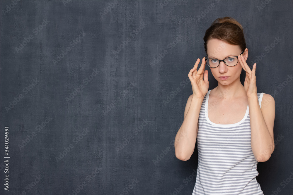 Portrait of serious girl with glasses, touching frame with both hands Portrait of serious girl with glasses, touching frame with both hands