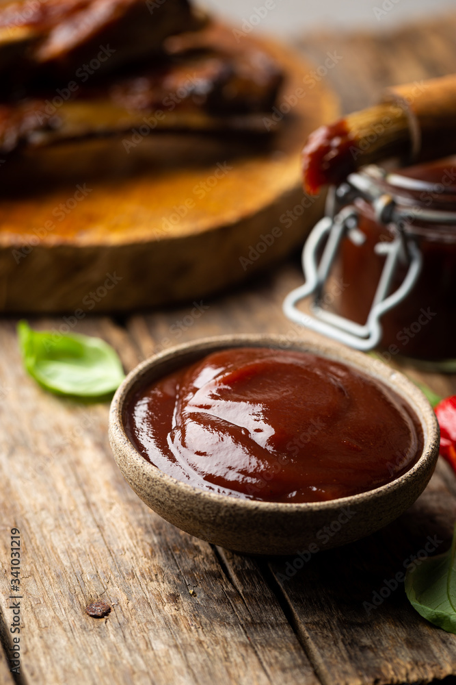 Barbecue sauce in a saucer with basting brush over rustic barn wood table with copy space. Barbecue sauce in a saucer with basting brush over rustic barn wood table with copy space.