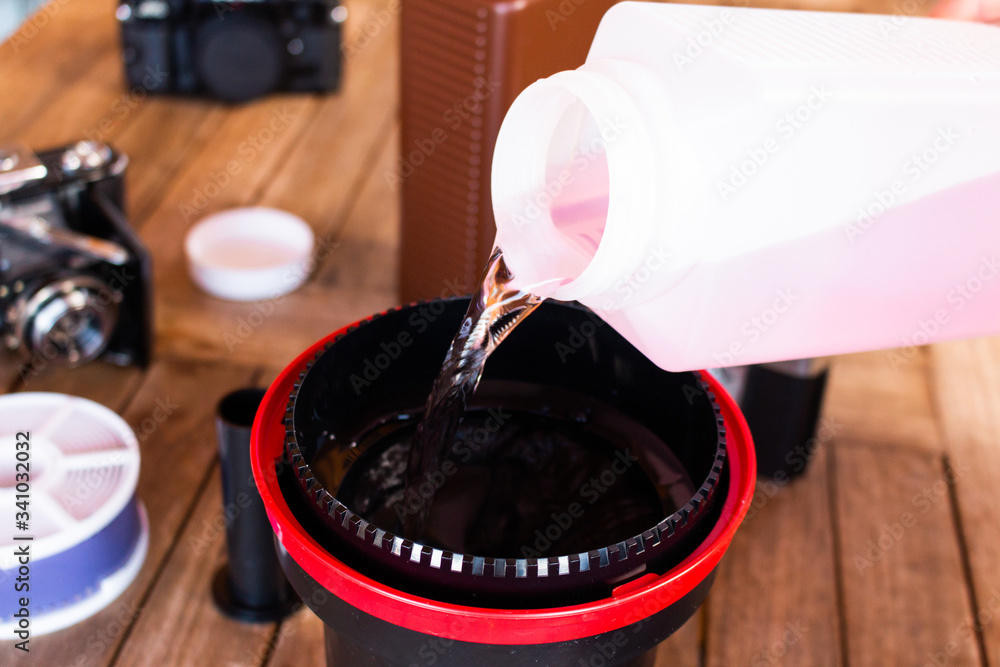 Αυτοκόλλητο pouring photo chemistry in a developing tank in order to develope analog film at