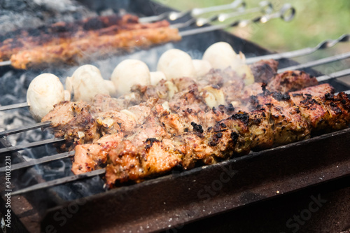 Cooking barbecue on a metal skewer. Grilled meat cooked on the barbecue. Skewers of fresh beef meat cut into slices. Traditional oriental dish, barbecue. Charcoal and flame grill, picnic, street food