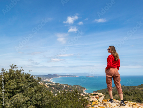 Cheerful girl dressed in red enjoying the coast and looking at the sea.