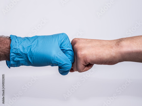 Dramatic fist bump with a blue medical glove and a bruised and dirty woman's hand. Showing appreciation to medical professionals for their hard work. Profile view on white background.