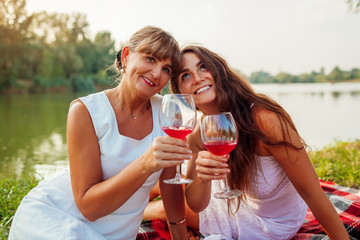 Mother's day. Mother drinking wine with her adult daughter in spring park. Family having picnic outdoors.