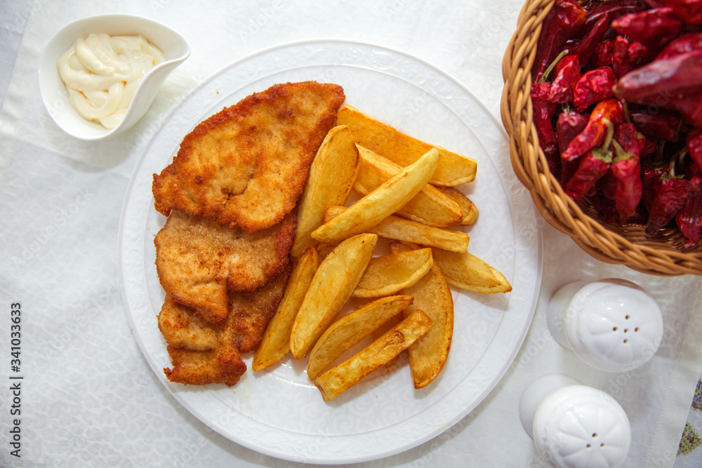 Fried chicken cutlet. Fry the potatoes in a white plate . Red Dry Pepper in Traditional Basket . Mayonnaise inside a bowl . Fried chicken cutlet. Fry the potatoes in a white plate . Red Dry Pepper in Traditional Basket . Mayonnaise inside a bowl .