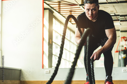 Crossfit in the gym with ropes. The athlete is training.