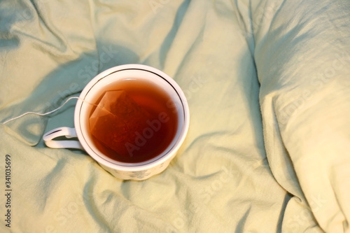 Tea in a vintage porcelain cup on a bed. Selective focus.