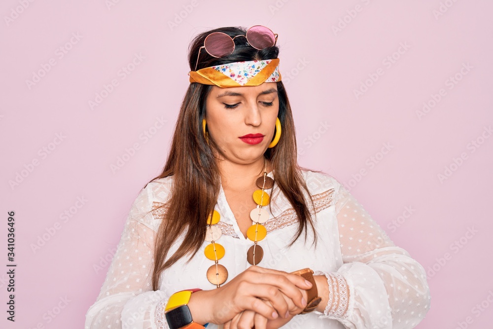 Young hispanic hippie woman wearing fashion boho style and sunglasses over pink background Checking the time on wrist watch, relaxed and confident Young hispanic hippie woman wearing fashion boho style and sunglasses over pink background Checking the time on wrist watch, relaxed and confident