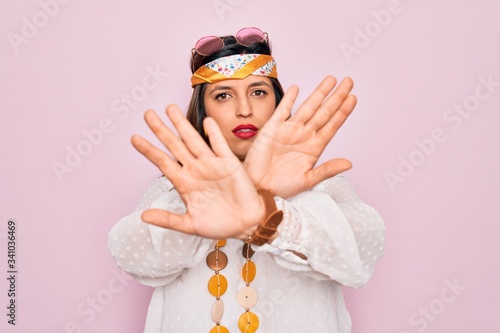 Young hispanic hippie woman wearing fashion boho style and sunglasses over pink background Rejection expression crossing arms doing negative sign, angry face