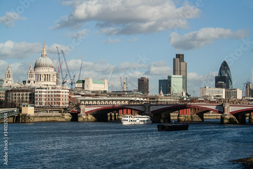London city skyline with river, boats, bridge and clouds