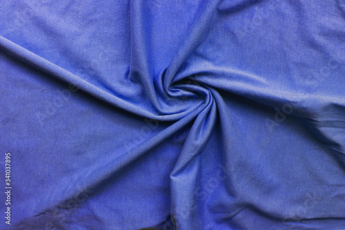 Creased blue fabric background. Cotton cloth wrinkled texture. Top view of crumpled bed linen sheets, vivid elegant blue fabric texture
