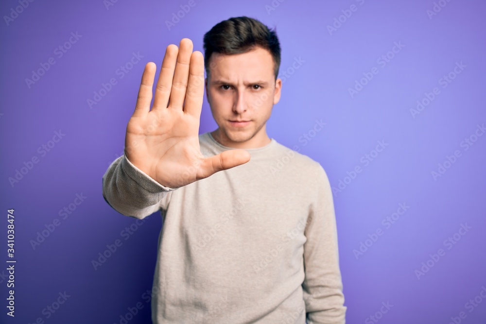 Young handsome caucasian man wearing casual sweater over purple isolated background doing stop sing with palm of the hand. Warning expression with negative and serious gesture on the face. Young handsome caucasian man wearing casual sweater over purple isolated background doing stop sing with palm of the hand. Warning expression with negative and serious gesture on the face.