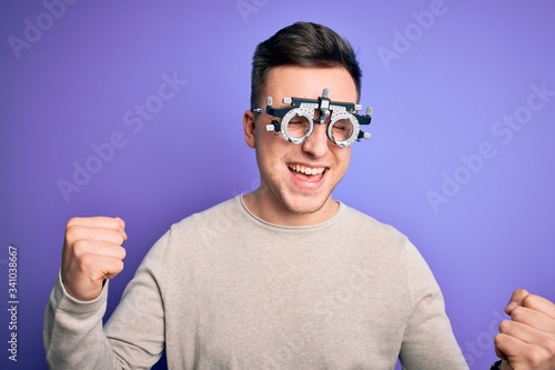Young handsome caucasian man wearing optometrical glasses over purple background very happy and excited doing winner gesture with arms raised  smiling and screaming for success. Celebration concept.